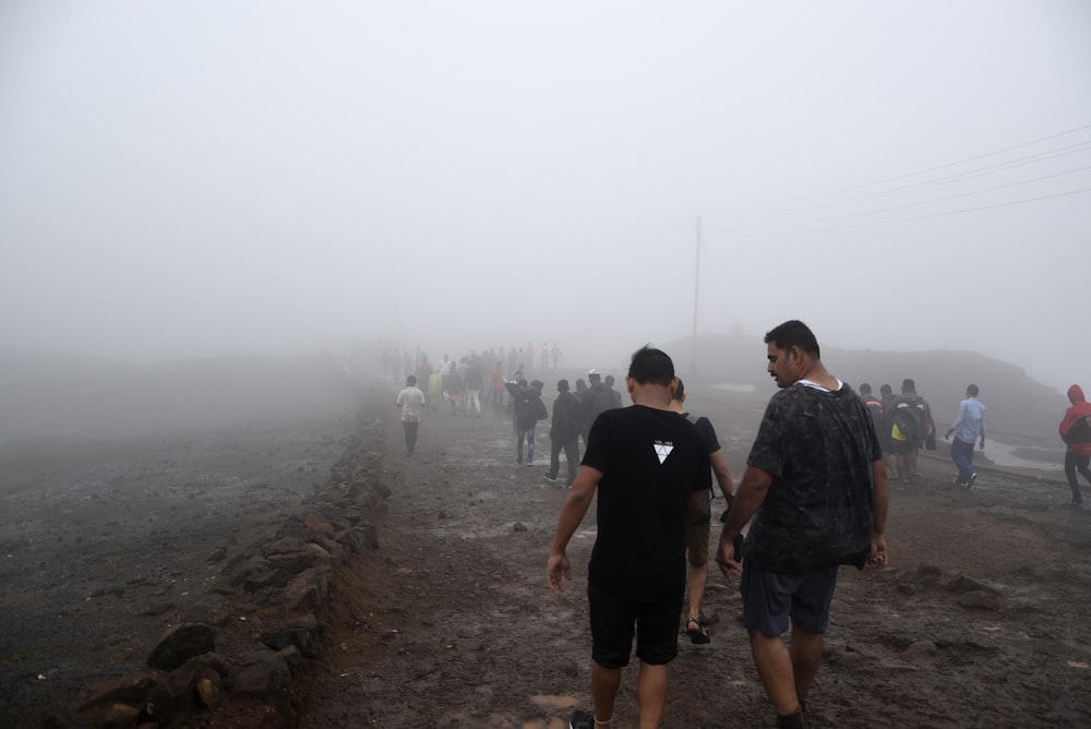 people walking on dirt road with fog