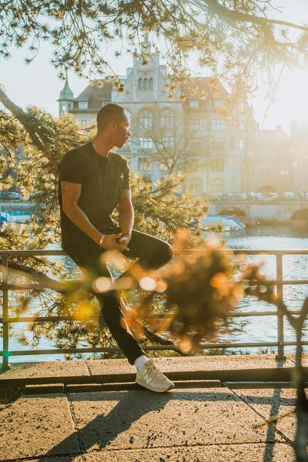 man sitting on metal railings beside the river