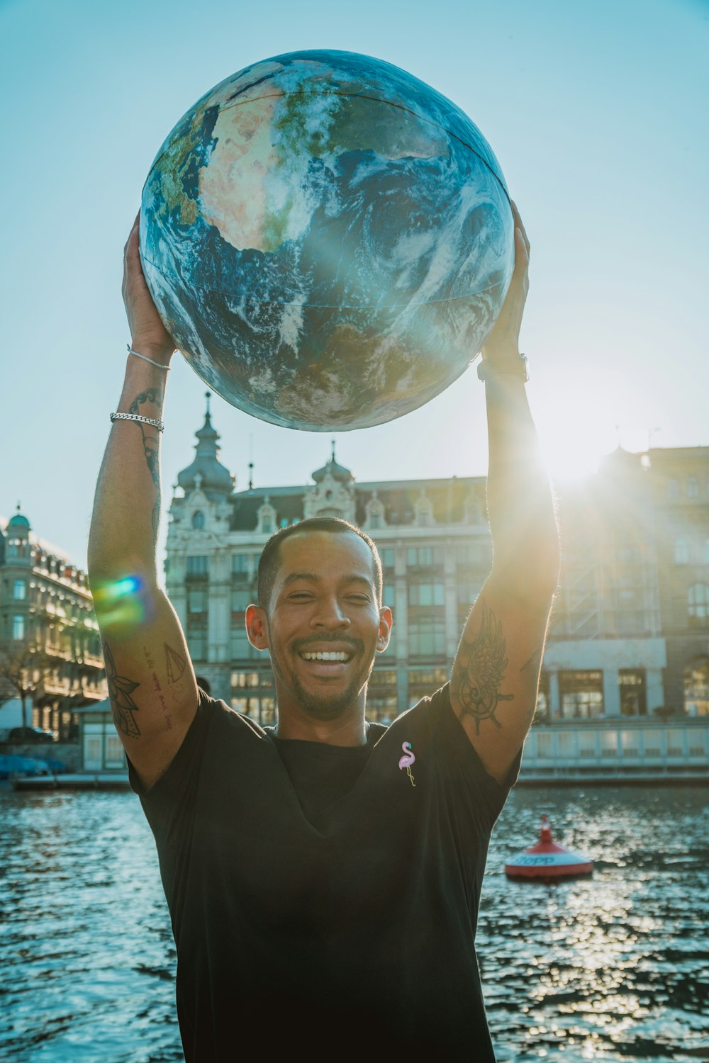 man holding globe near body of water