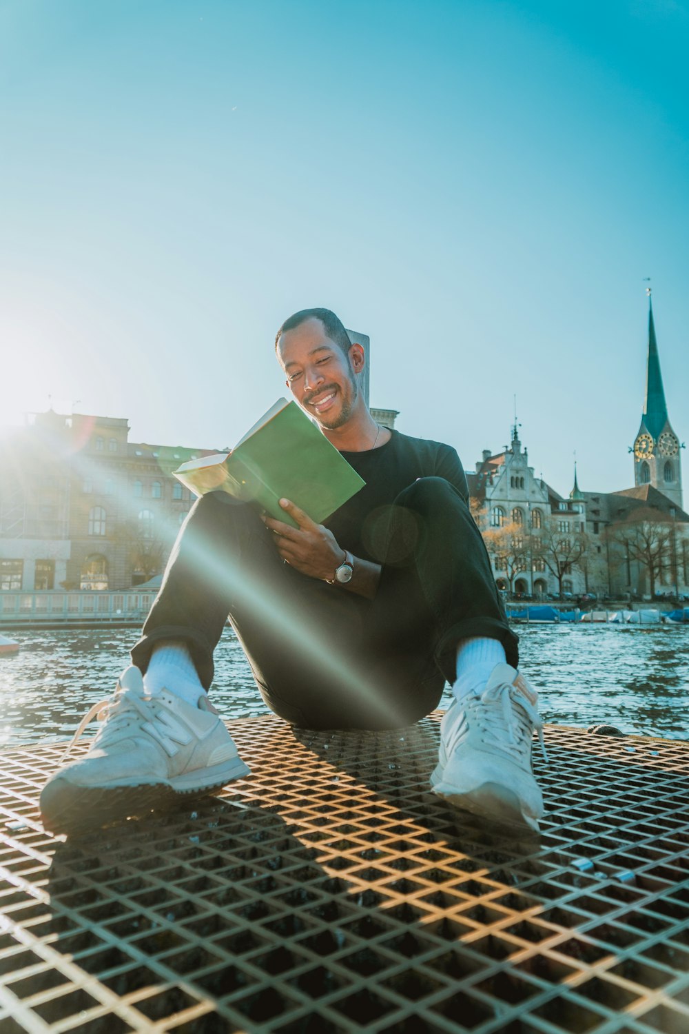 man reading book by a river