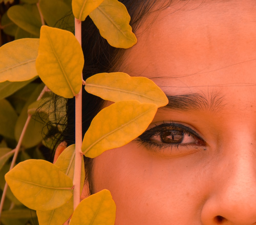 a woman's face with leaves covering her eyes