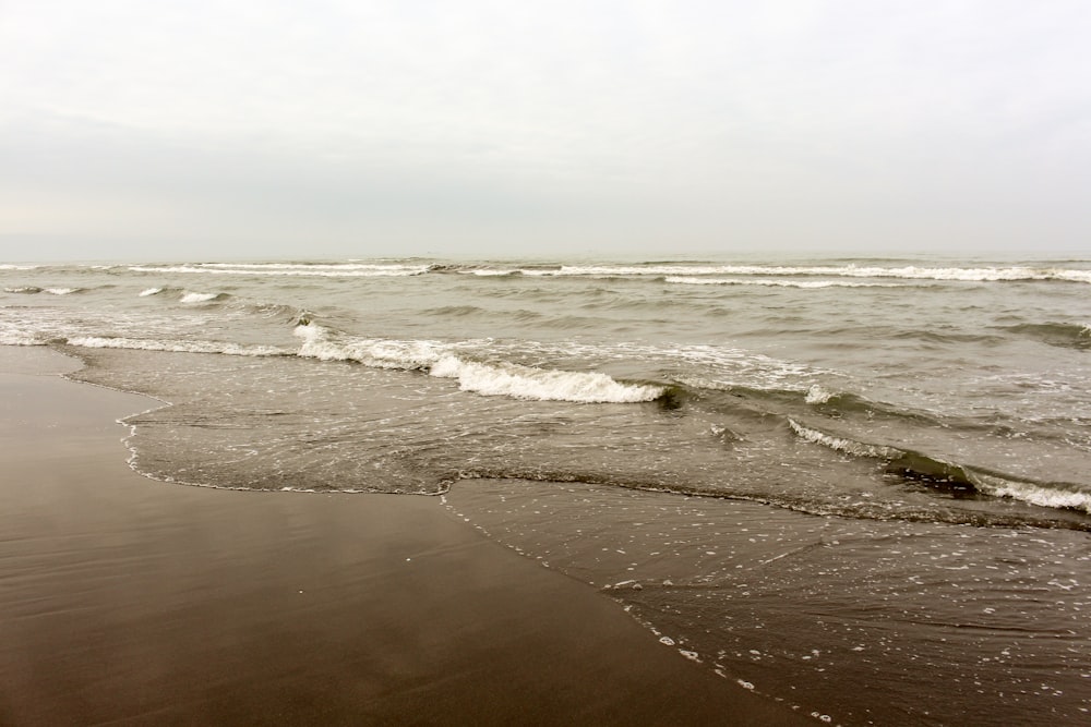 ocean waves crashing on sand during daytime