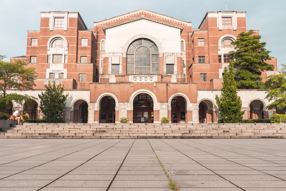 green trees in front of brown and white concrete multi-story building during daytime