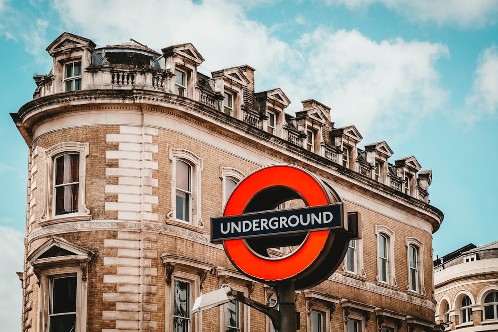 round red and black Underground sign near brown concrete building