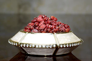 A sleek decorative centerpiece bowl filled with seasonal fruits, resting elegantly on a textured table runner.