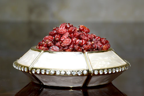 A sleek decorative centerpiece bowl filled with seasonal fruits, resting elegantly on a textured table runner.