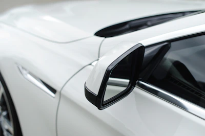 Side mirror reflecting a sleek, high-contrast silhouette of a luxury vehicle.