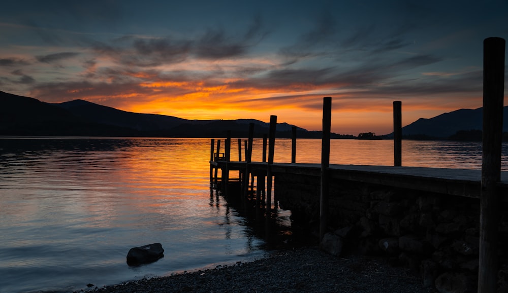 silhouette photography of dock in lake