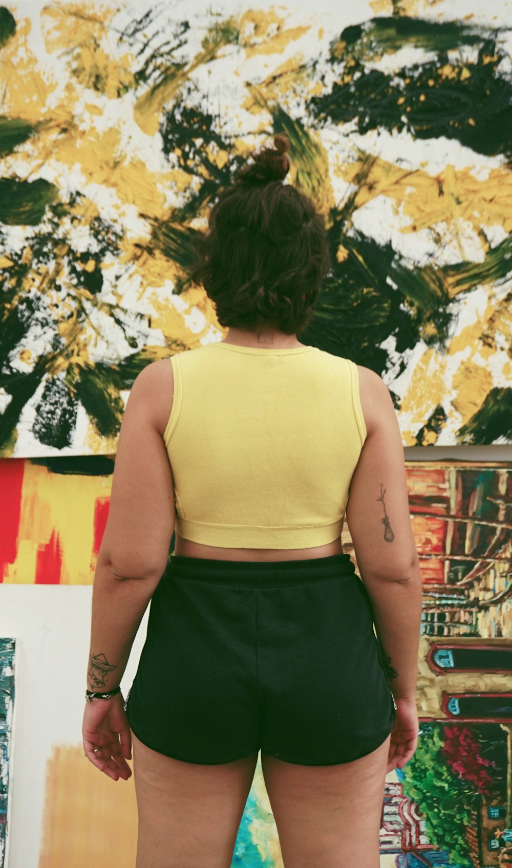 mulher em pé vestindo crop-top amarelo e shorts pretos