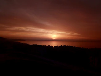 Sunset over the Mediterranean coast of Tanger, with warm orange and pink hues.