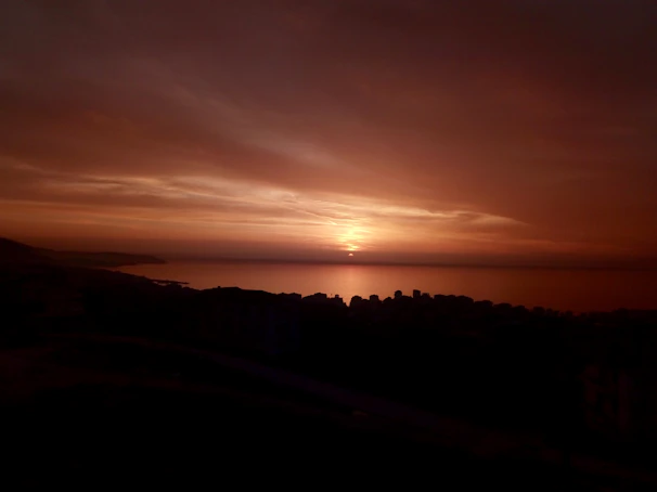 Sunset over the Mediterranean coast of Tanger, with warm orange and pink hues.