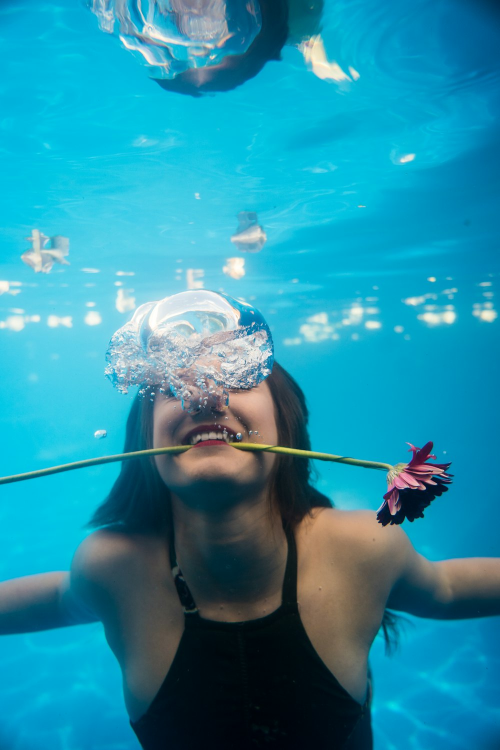 woman diving on water biting flower