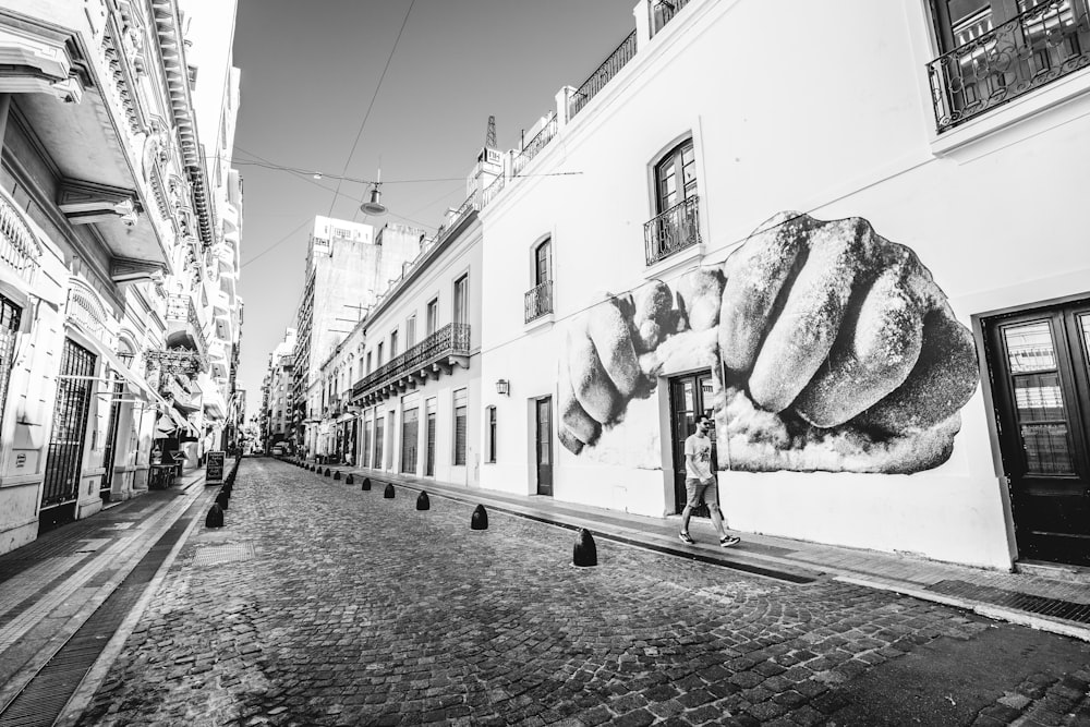 grayscale photography of man walking on sidewalk