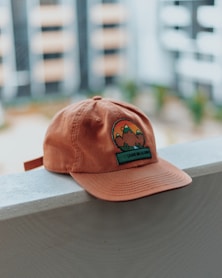 orange and green mountain embroidered cap on pavement