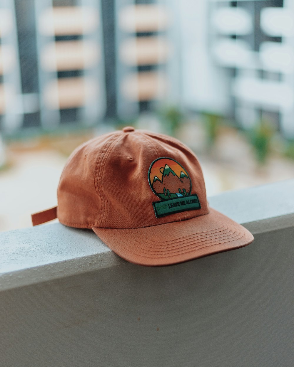 berretto ricamato di montagna arancione e verde sul marciapiede