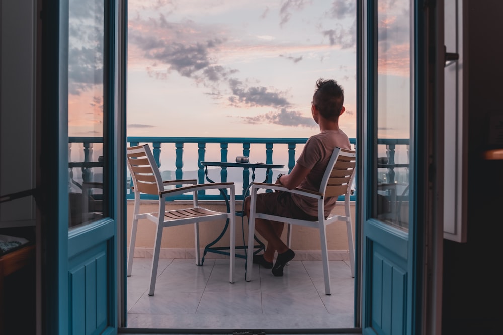 man sitting on veranda overlooking sea at sunset