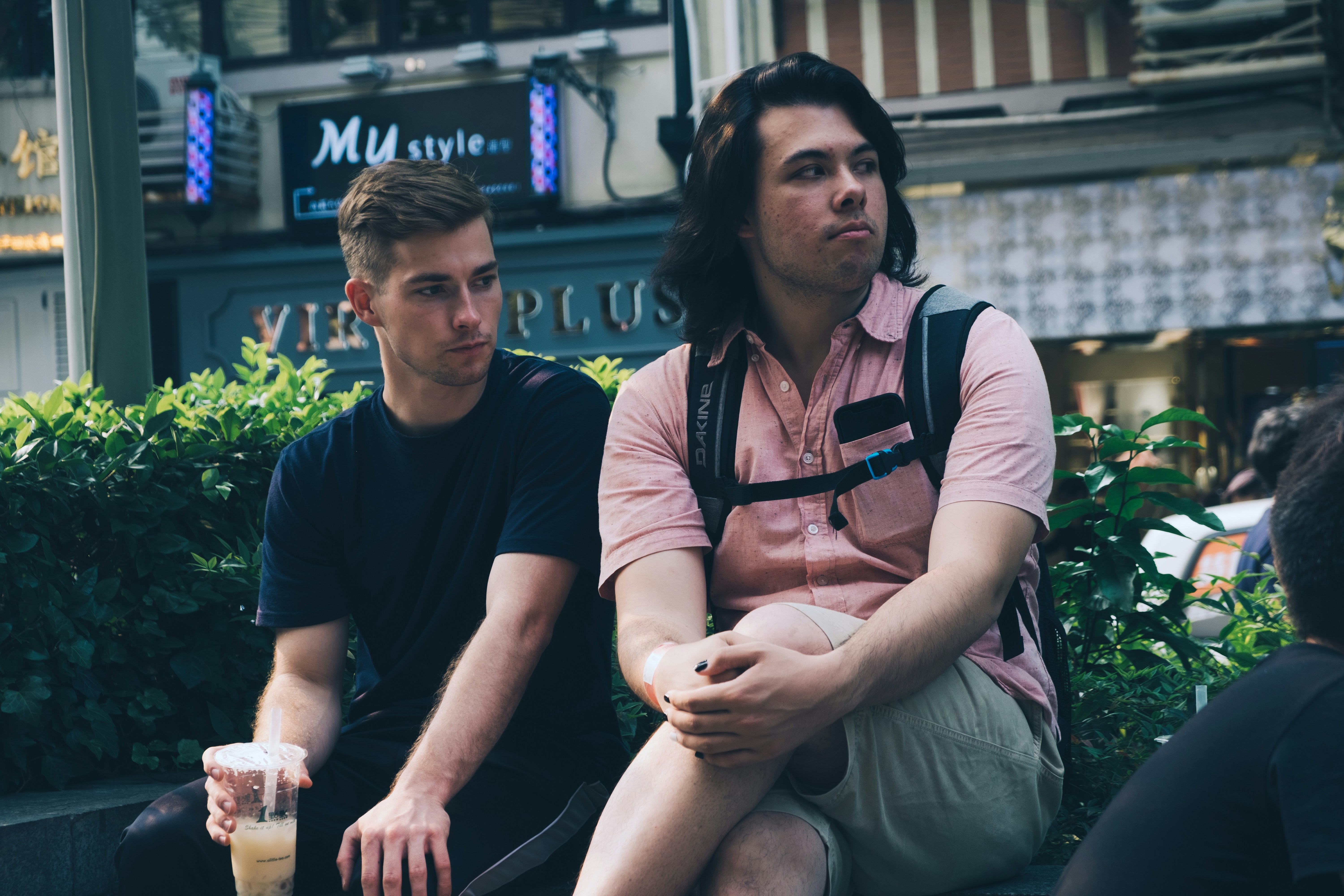 man sitting with cross legs beside another man near green leaf plants