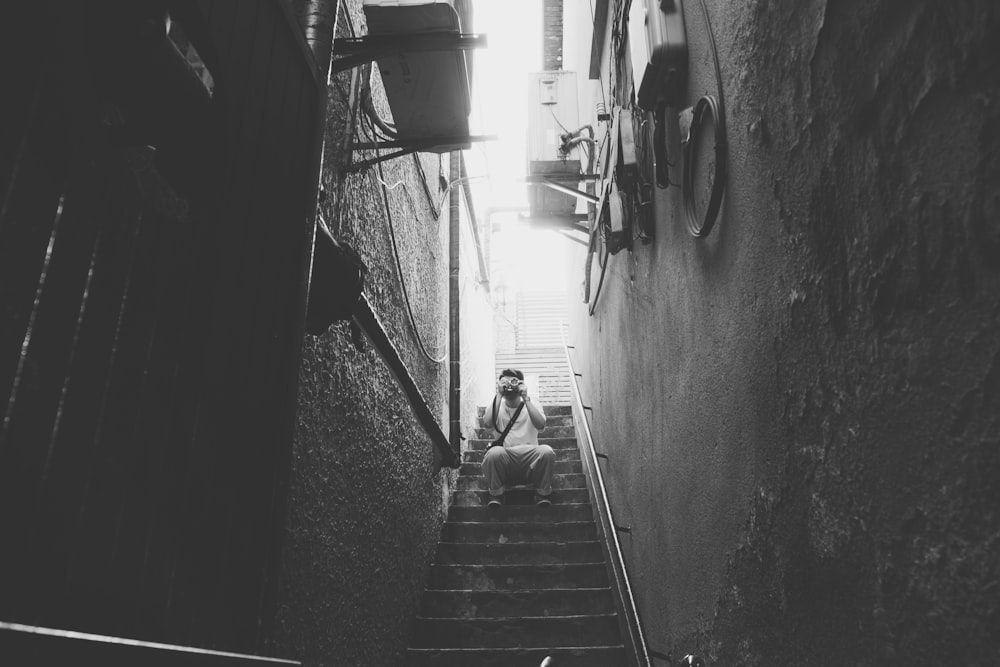 grayscale photography of man sitting on stair