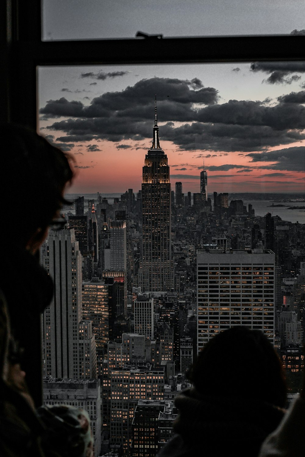 persona che guarda l'Empire State Building dalla finestra di vetro al crepuscolo