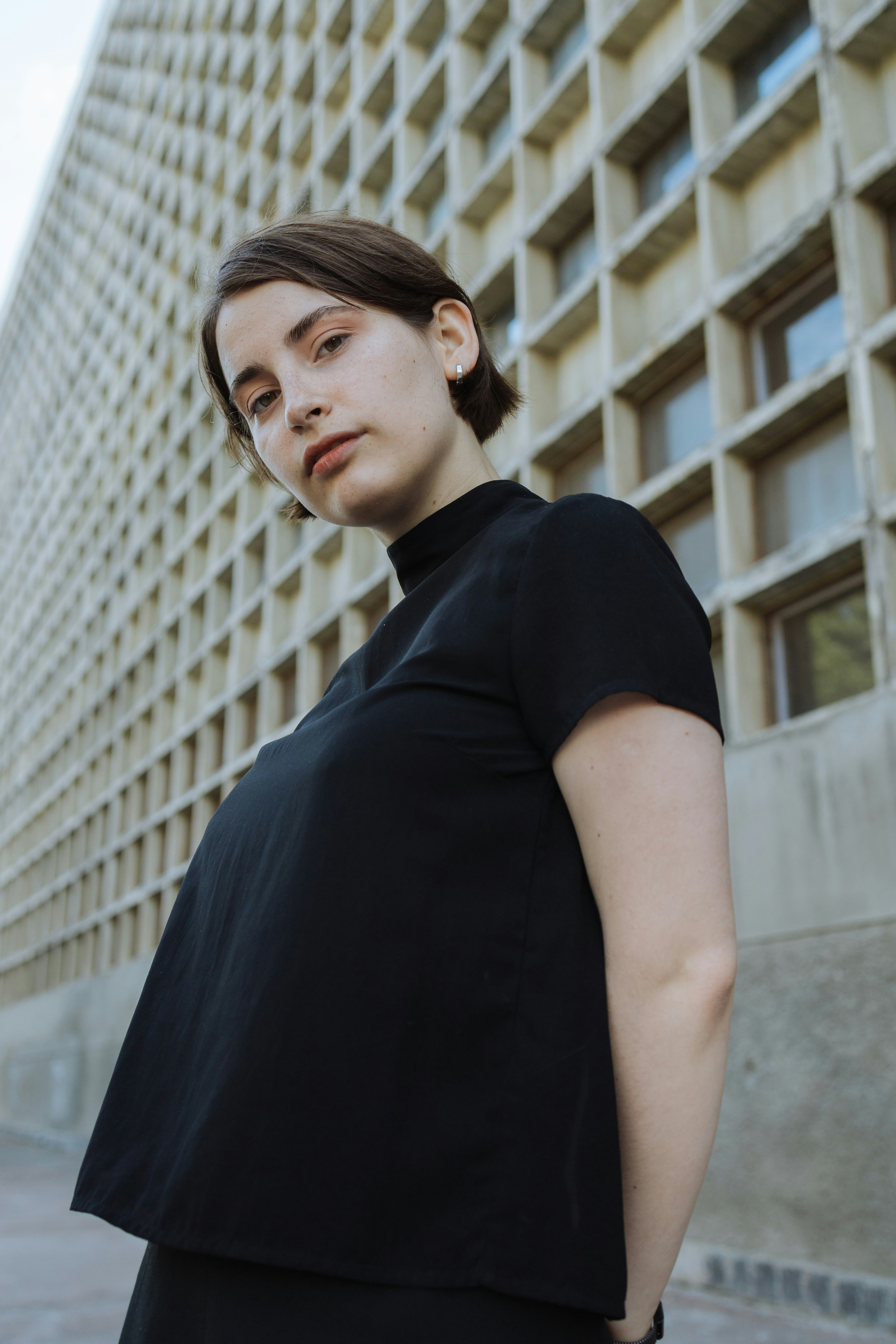 灰色の建物のそばにいる黒服の女性の写真 Unsplashで見つけるグレーの無料写真