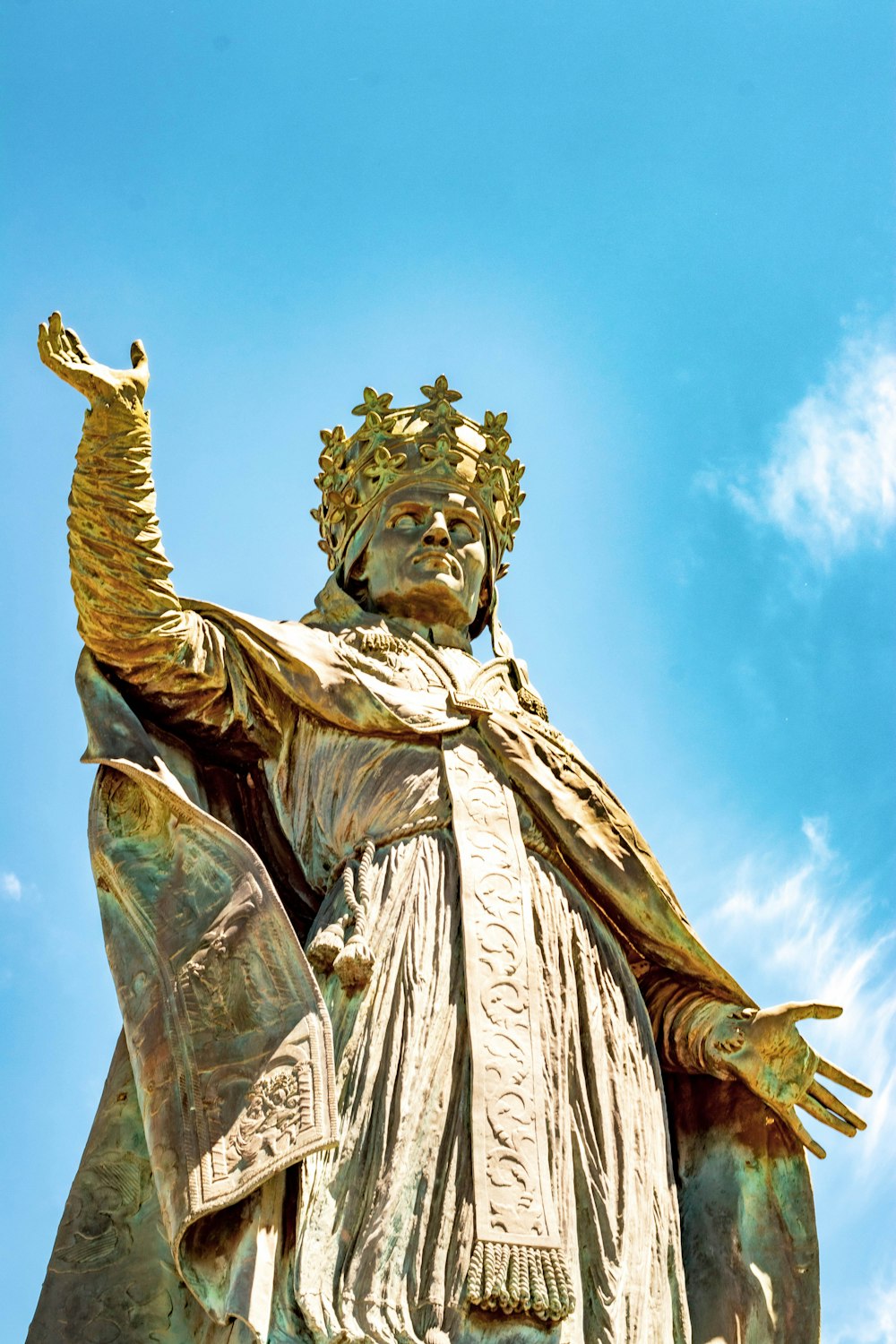 close-up photography of man wearing cape and crown statue during daytime