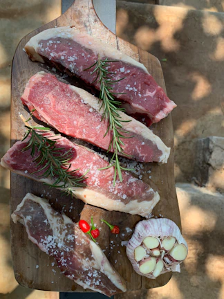 Close-up of thinly sliced carne seca arranged on rustic wooden board.