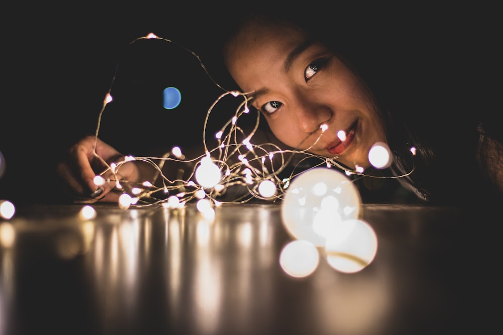 smiling woman beside string lights