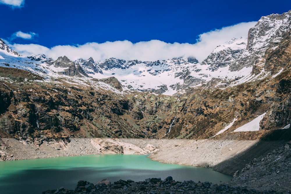 body of water near mountain under blue sky