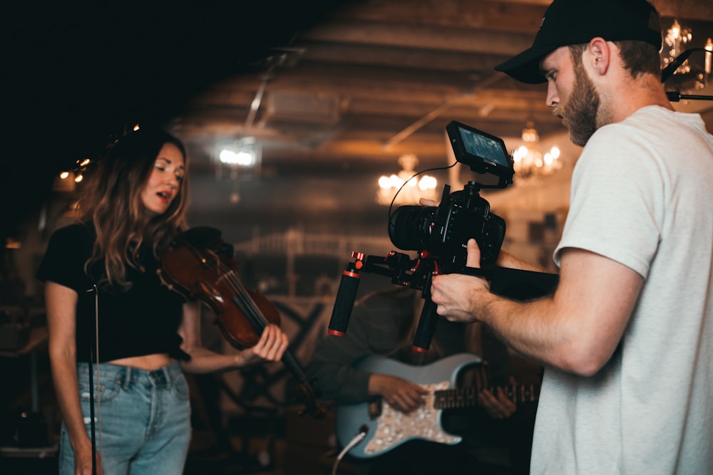 man taking video of woman holding violin