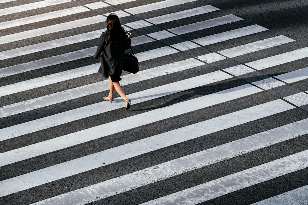 woman in black coat crossing pedestrian
