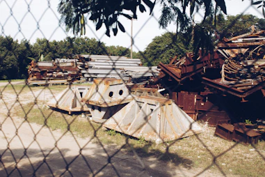Stacks of sorted scrap metal ready for transport in a sunny industrial yard.