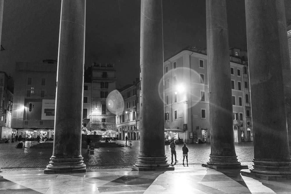 due persone vicino a un edificio fotografia in scala di grigi