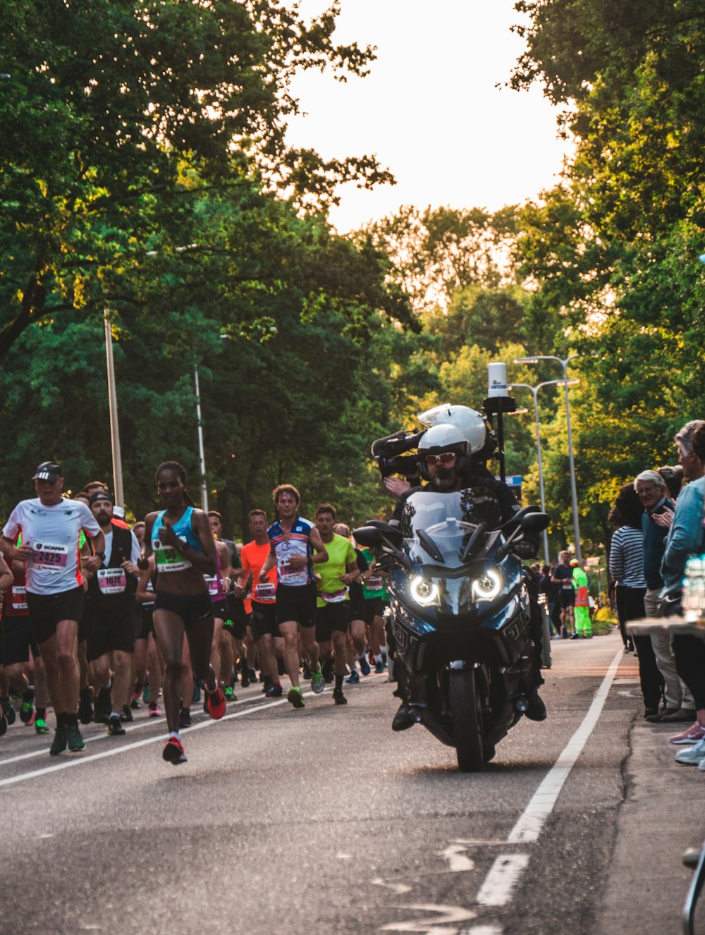 man riding touring motorcycle beside runners during daytime