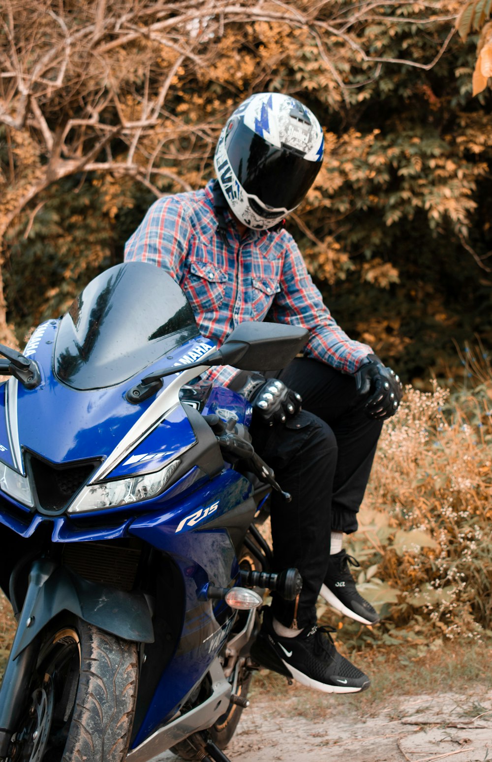 Homme portant un casque blanc assis sur une moto de sport bleue