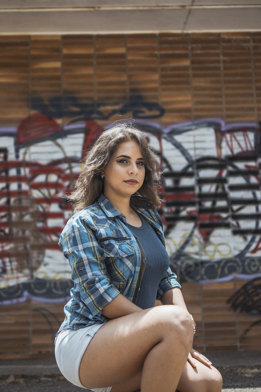 woman in black crew-neck shirt and white shorts posing near wall with grafitti