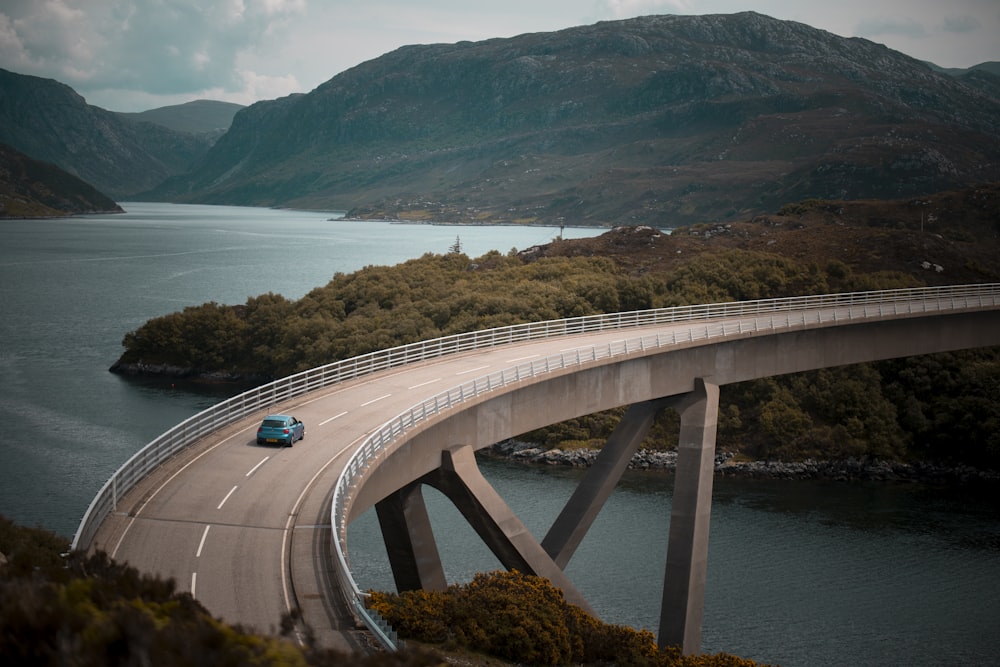 blue vehicle driving on bridge during daytime