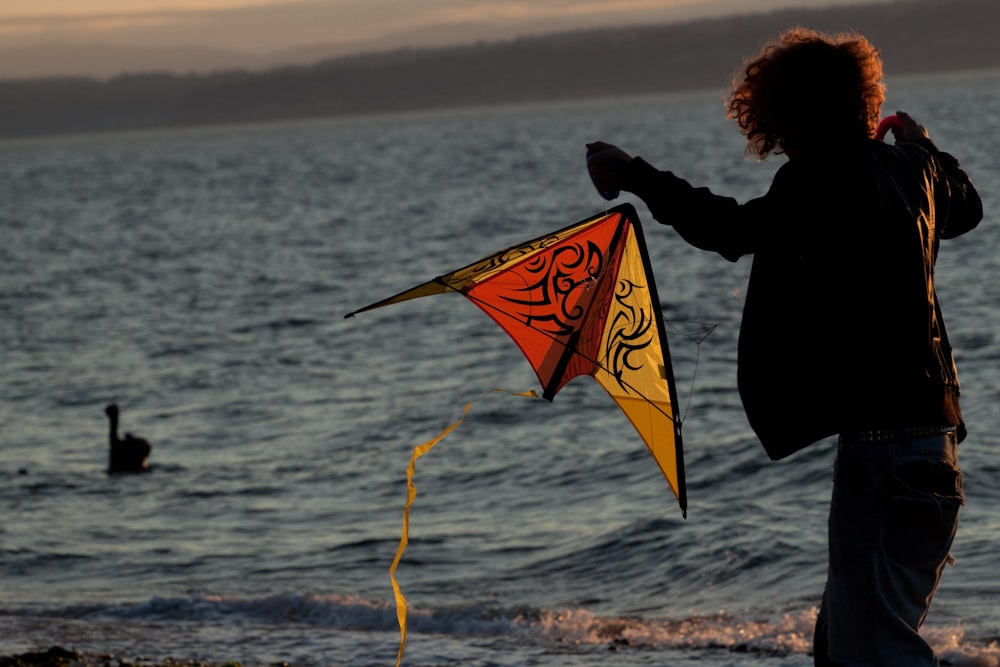 man standing on beach holding kite