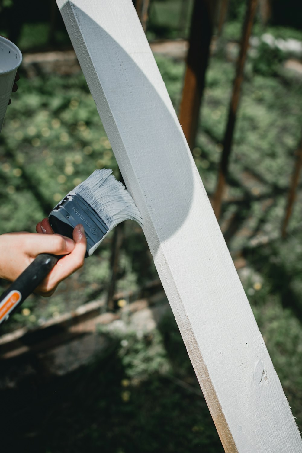 person painting white wood plank