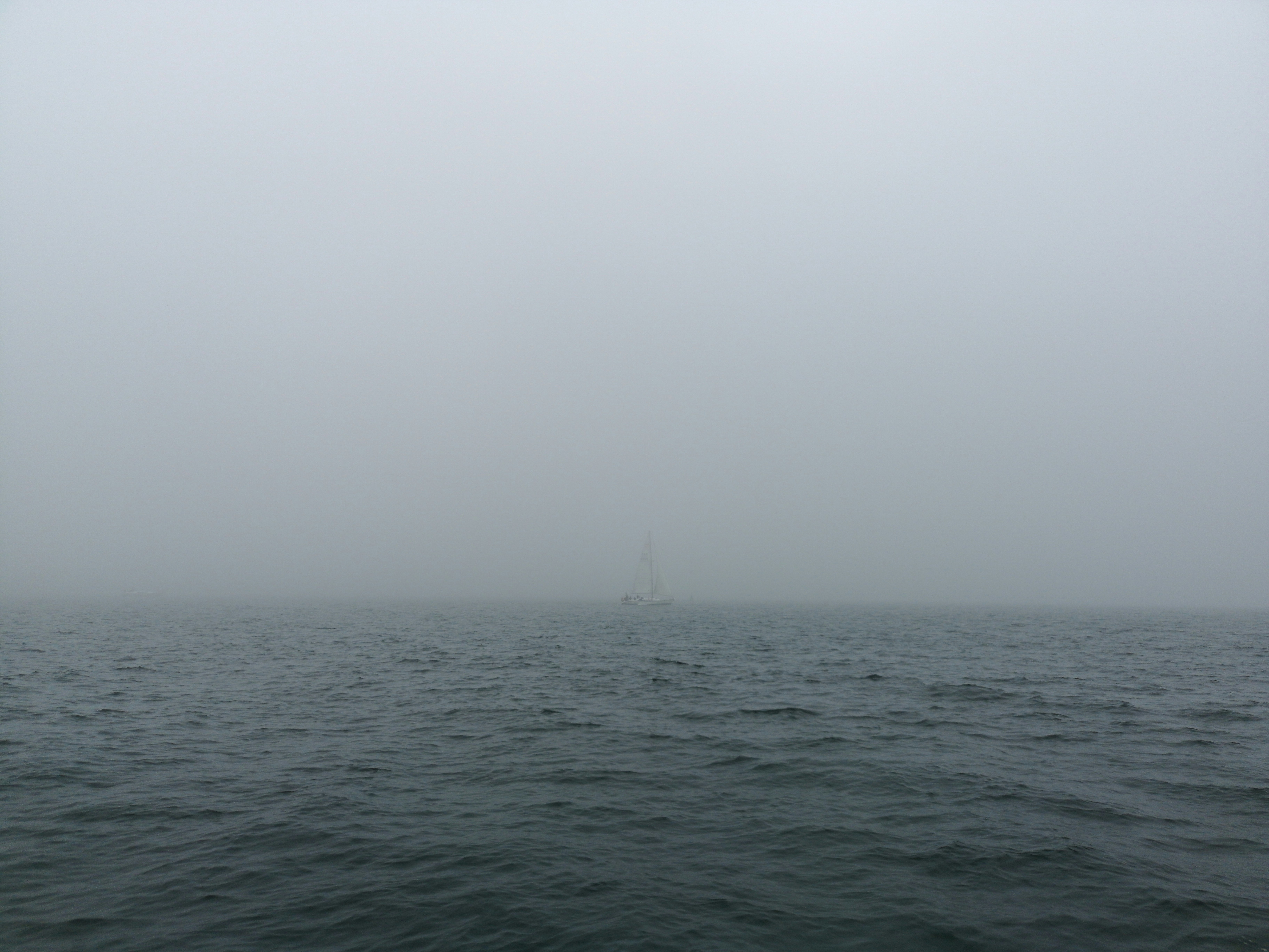landscape photo of a white sailboat on a foggy body of water