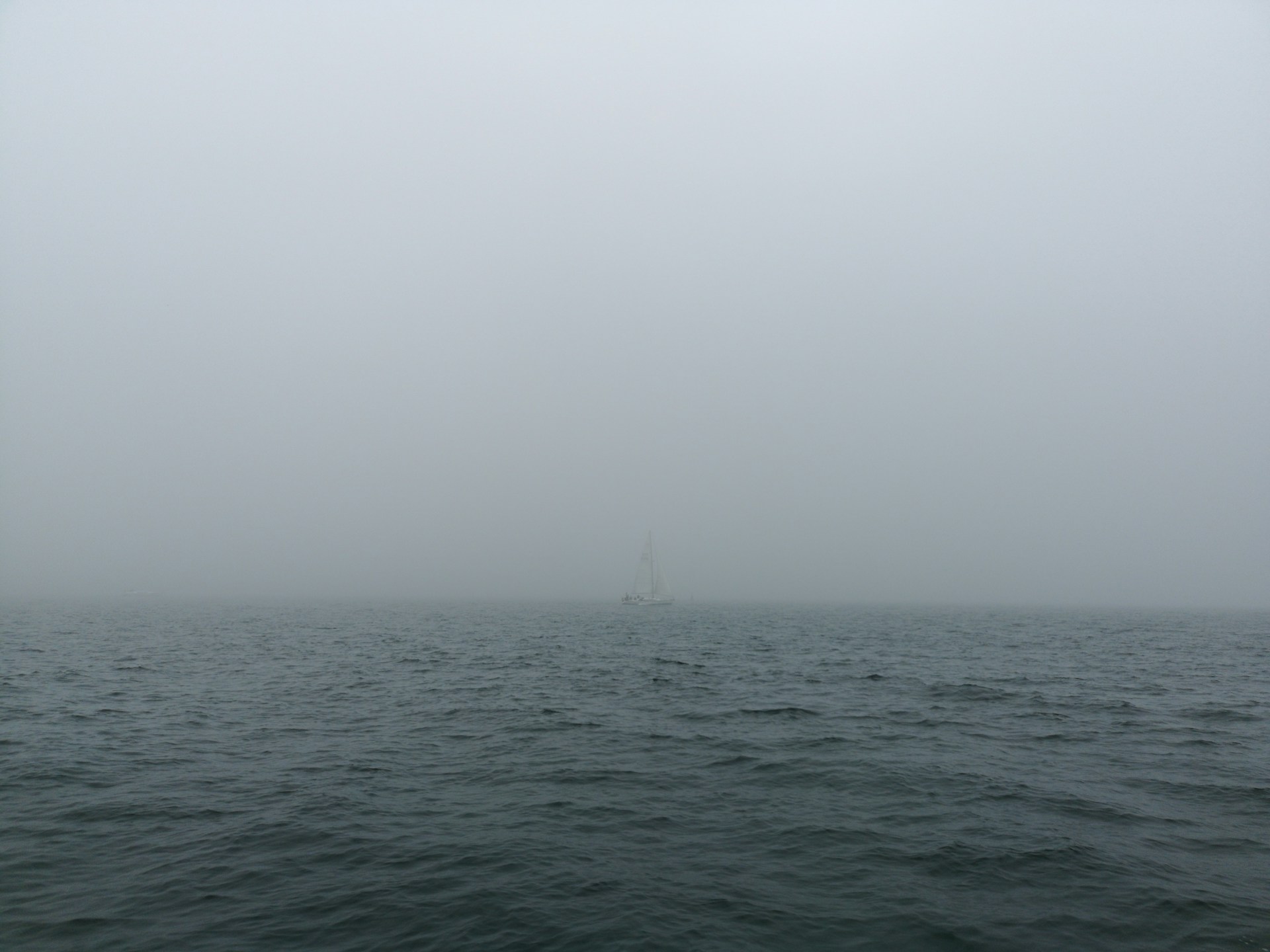 landscape photo of a white sailboat on a foggy body of water