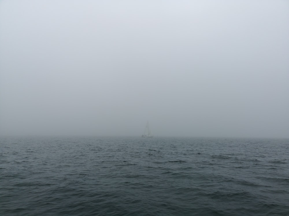 landscape photo of a white sailboat on a foggy body of water