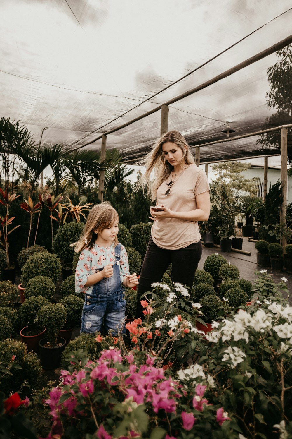 woman and girl standing near flowers