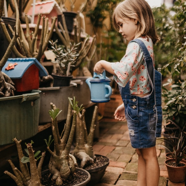 kid holding a bucket near plant during daytime close-up photography