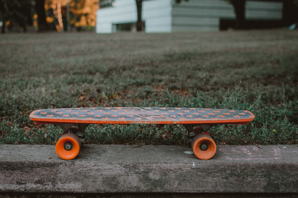gray and orange skateboard on curb