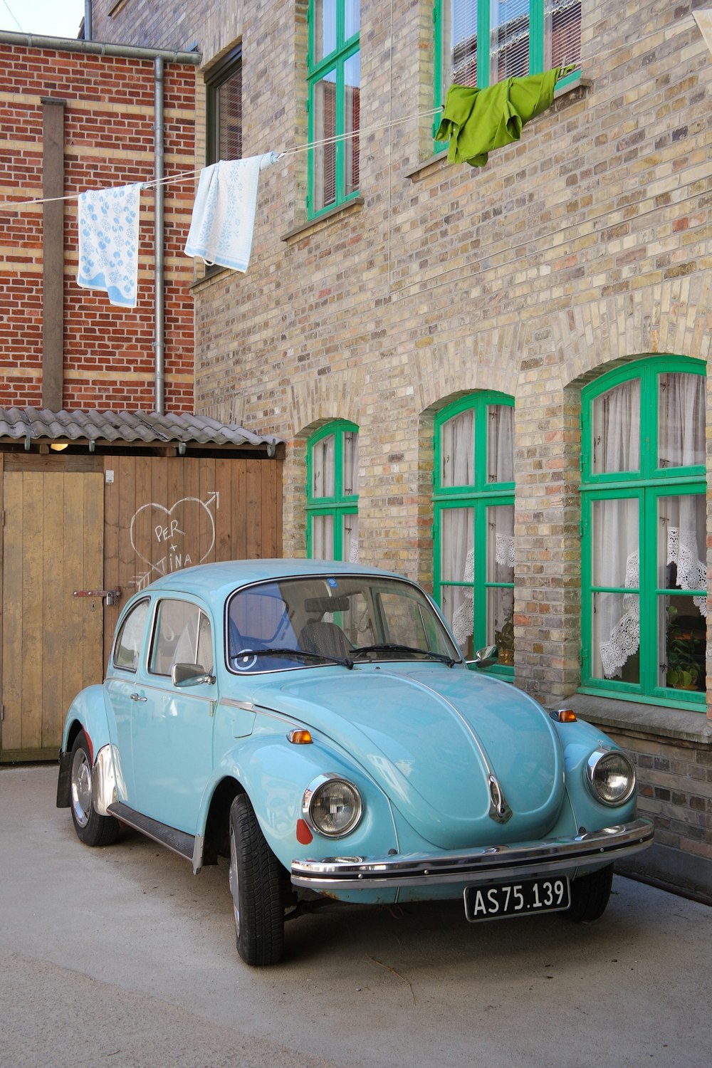 parked teal Volkswagen Beetle coupe beside wall