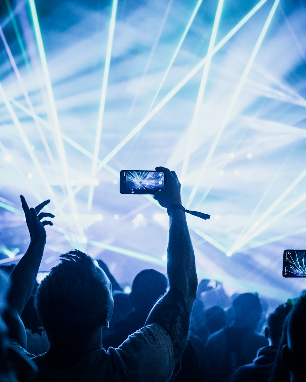 man standing on crowd and recording event on his phone