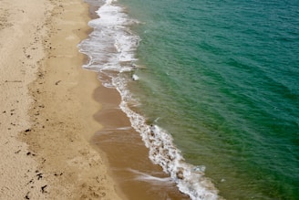A natural pool on a sandy beach with gentle waves.