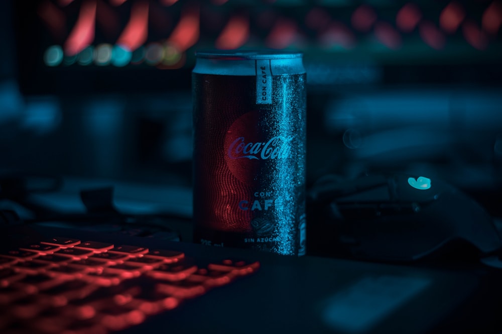 Lata de refresco de Coca-Cola al lado del teclado mecánico