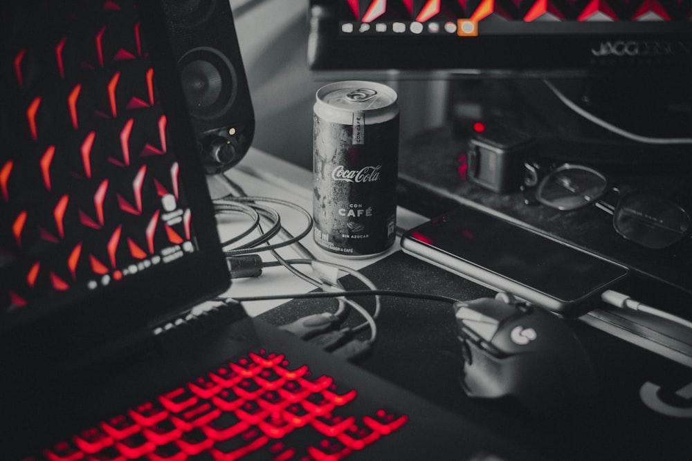 Coca-Cola soda can beside smartphone, mousepad with mouse, and gaming laptop