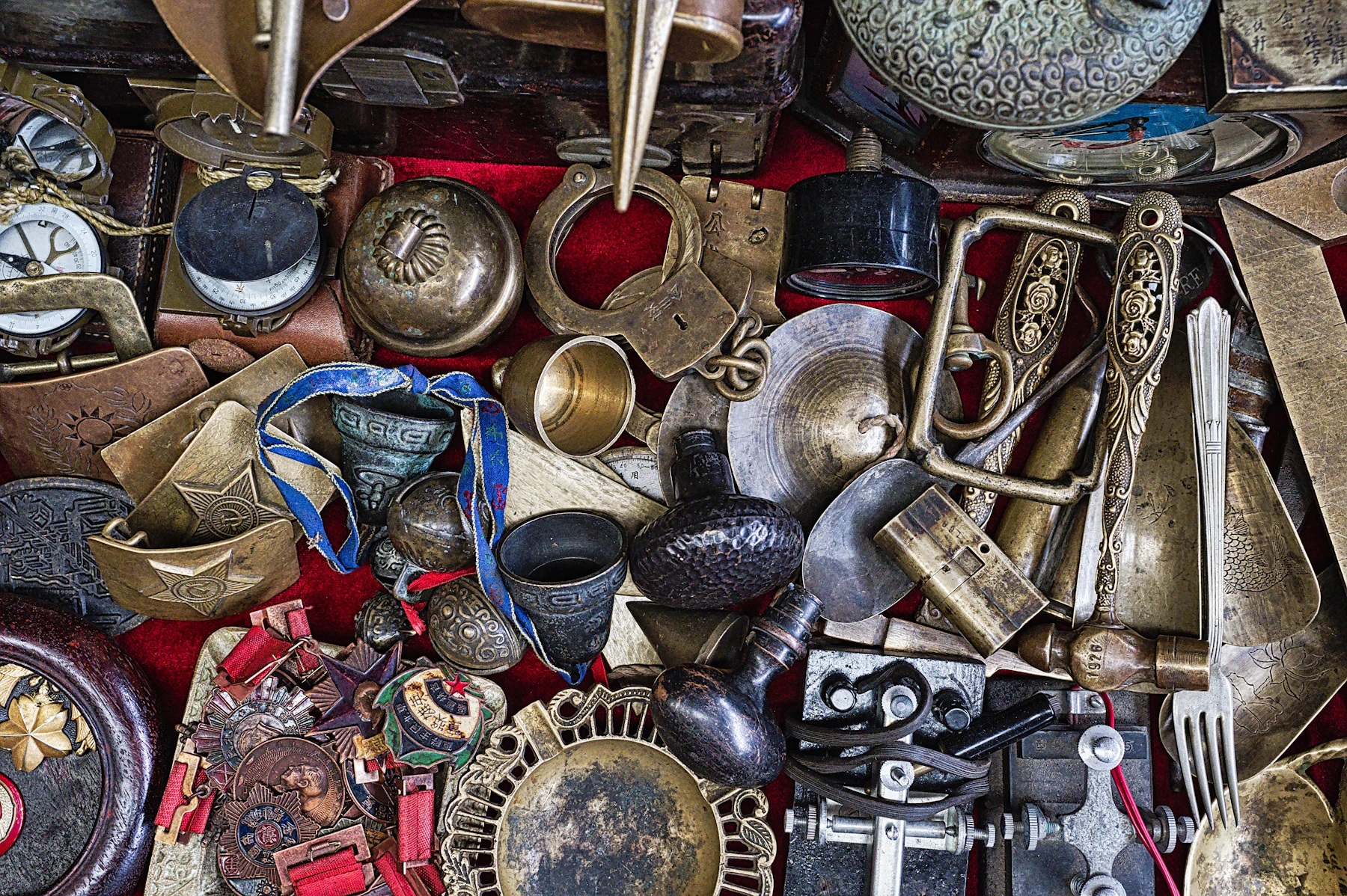 A dense pile of old brass and metalware, including bells, buckles, medals, ladles and trays